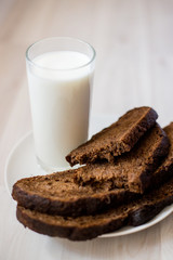 a glass of milk and slices of rye bread on a saucer
