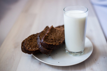 a glass of milk and slices of rye bread on a saucer