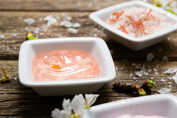 cosmetics and cherry blossom on old wooden table background