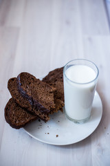 a glass of milk and slices of rye bread on a saucer