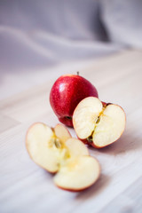 one whole and one sliced red apple on a light background