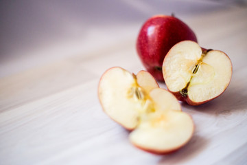 one whole and one sliced red apple on a light background