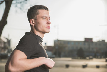 Beautiful, slender young man in black t-shirt on black background and on the street