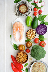 Fresh salmon with vegetables and nuts. Variety of vegetables and nuts for healthy diet. Light wooden background, top view