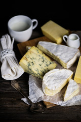 camembert cheese and a set of cheeses on a wooden board on a dark background