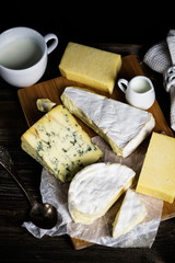 camembert cheese and a set of cheeses on a wooden board on a dark background