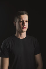 Beautiful, slender young man in black t-shirt on black background and on the street