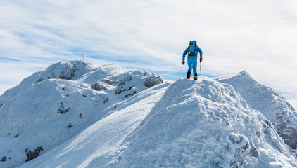 Fototapeta na wymiar Hiker on the snow-ice ridge. Active winter holidays in the mountains.