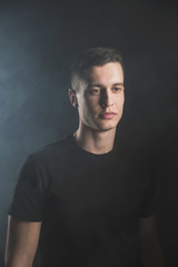 Beautiful, slender young man in black t-shirt on black background and on the street