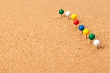 Group of thumbtacks pinned on corkboard