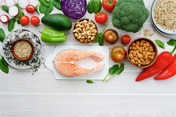 Fresh salmon with vegetables and nuts. Variety of vegetables and nuts for healthy diet. Light wooden background, top view