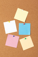 Cork board with several colorful blank notes with pins