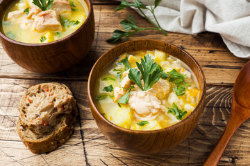 Fish soup in a wooden bowl with fresh herbs.