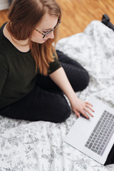 Young woman relaxing on a bed studying