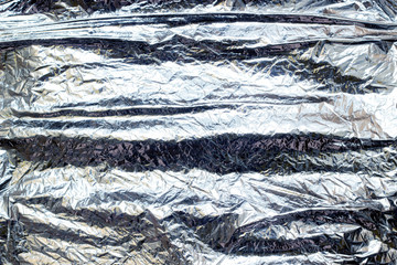 Thin sheet of silver leaf background with shiny uneven surface