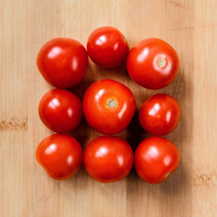 Red tomatoes on light wooden background. Healthy food. Top view. Square frame. Geometry and minimalism