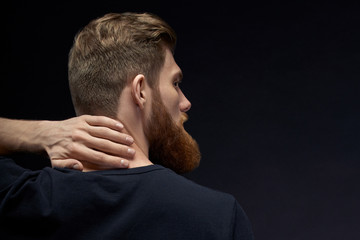 Handsome bearded man turned back. Pour over black background. Young model man with ginger hair