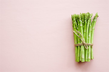 Bunch of fresh asparagus on delicate pink pastel background