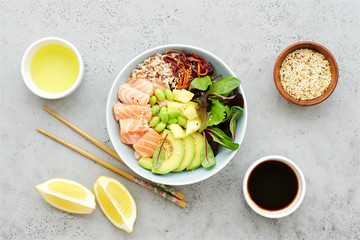 Salmon poke bowl with salad, avocado, edamame beans, pineapple and sesame Brown rice poke bowl Top view, clean eating concept Traditional Hawaiian dish