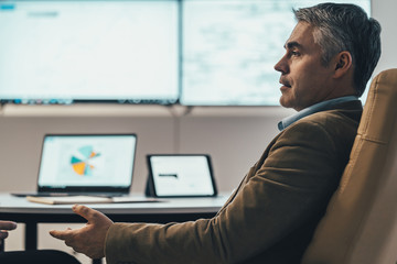 The businessman sitting at the table near a screen