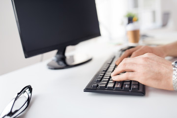business, people and technology concept - close up of male hands typing on computer keyboard at office