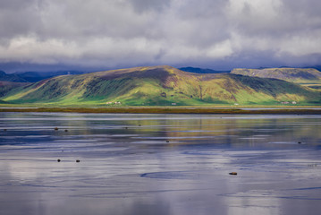 Reflection in the water of Dyrholaos estuary near cape Dyrholaey in Iceland