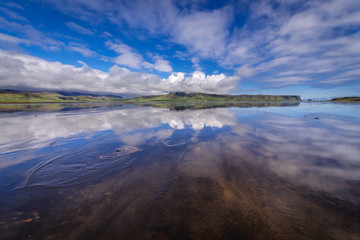 Reflection in the water of Dyrholaos estuary near cape Dyrholaey in Iceland