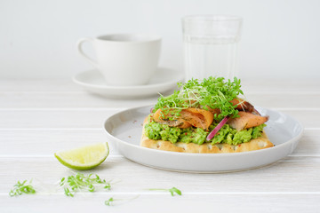 Smoked salmon sandwich with avocado cream. White wooden background