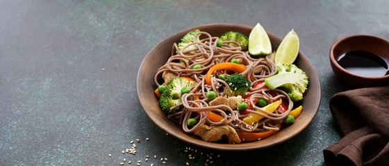 Stir fry noodles with chicken meat and vegetables in bowl on dark green background copy space