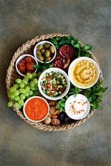 Meze plate with dip sauce and appetizers. Hummus, labneh, muhammar dip sauce in bowls on wicker tray