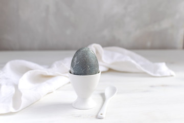 Naturally dyed easter egg for breakfast, dyed eggs in white basket, white egg cup, white wooden table - minimal easter concept