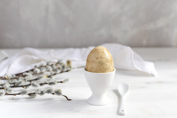 Naturally dyed easter egg for breakfast, white egg cup, draped napkin, white wooden table, willow...