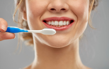 oral care, dental hygiene and people concept - close up of smiling woman with toothbrush cleaning...