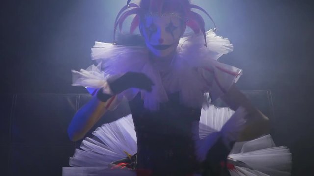 Horror circus with a creepy clown woman with white annd black makeup and red nose, slow motion