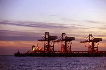 Fototapeta na wymiar A silhouette of a crane working at a pier