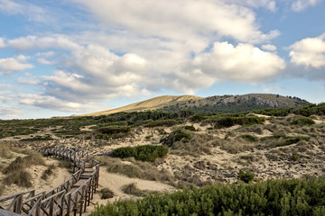 Fototapeta na wymiar Wooden walkway with beautiful sky, sand dunes and hills, cala mesquida, mallorca, spain.
