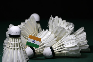 Fototapeta na wymiar Mini India flag stick on the heap of used shuttlecocks on green floor of Badminton court.