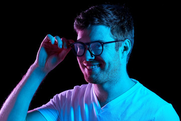people concept - portrait of young man in glasses and t-shirt over ultra violet neon lights in dark...