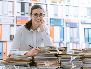 Smiling office clerk and piles of paperwork