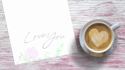 Handwritten Love You card with floral decoration next to a mug with coffee on a rustic wooden table. Top view and empty copy space for Editor's text