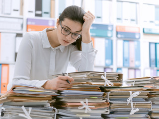 Sad young office worker overloaded with work