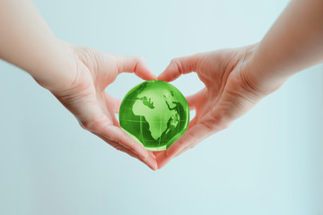 Hands in shape of heart  holding green glass globe of Africa and Europe