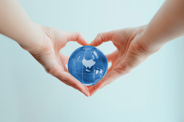 Hands in shape of heart  holding blue glass globe of Australia