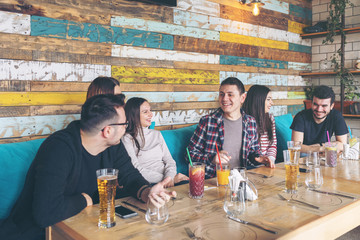 Happy group of best friends having fun over beer and refreshment in trendy popular pub