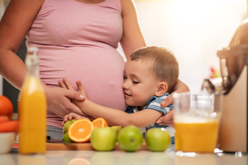 Mother and her kid making fresh orange juice in kitchen