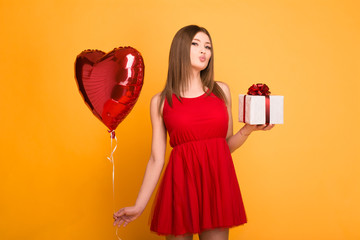 happy blonde in red dress holding a balloon and a gift box