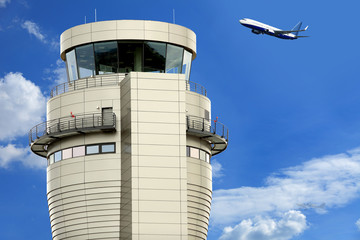 Wieża portu lotniczego na tle błękitnego nieba, samolot w   czasie startu.