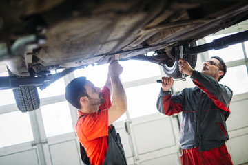 Profecional car mechanic changing motor oil at maintenance repair service station