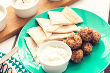 Fried minced meat with sauce and tortillas, traditional Greek lunch on a green plate in a restaurant.