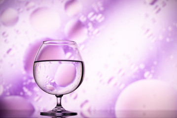 transparent glasses with water with oily drops on colorful background 